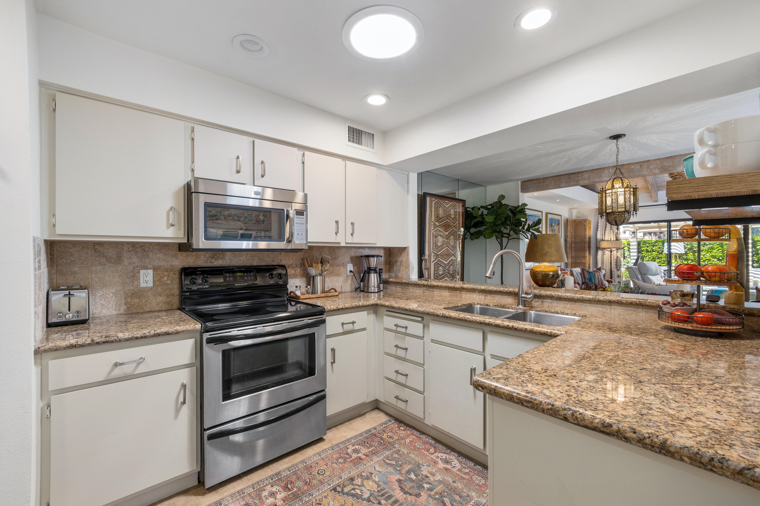 303 Forest Hills Drive Rancho Mirage, CA 92270 - Photo 29 of 72 a kitchen with kitchen island granite countertop a stove sink and cabinets