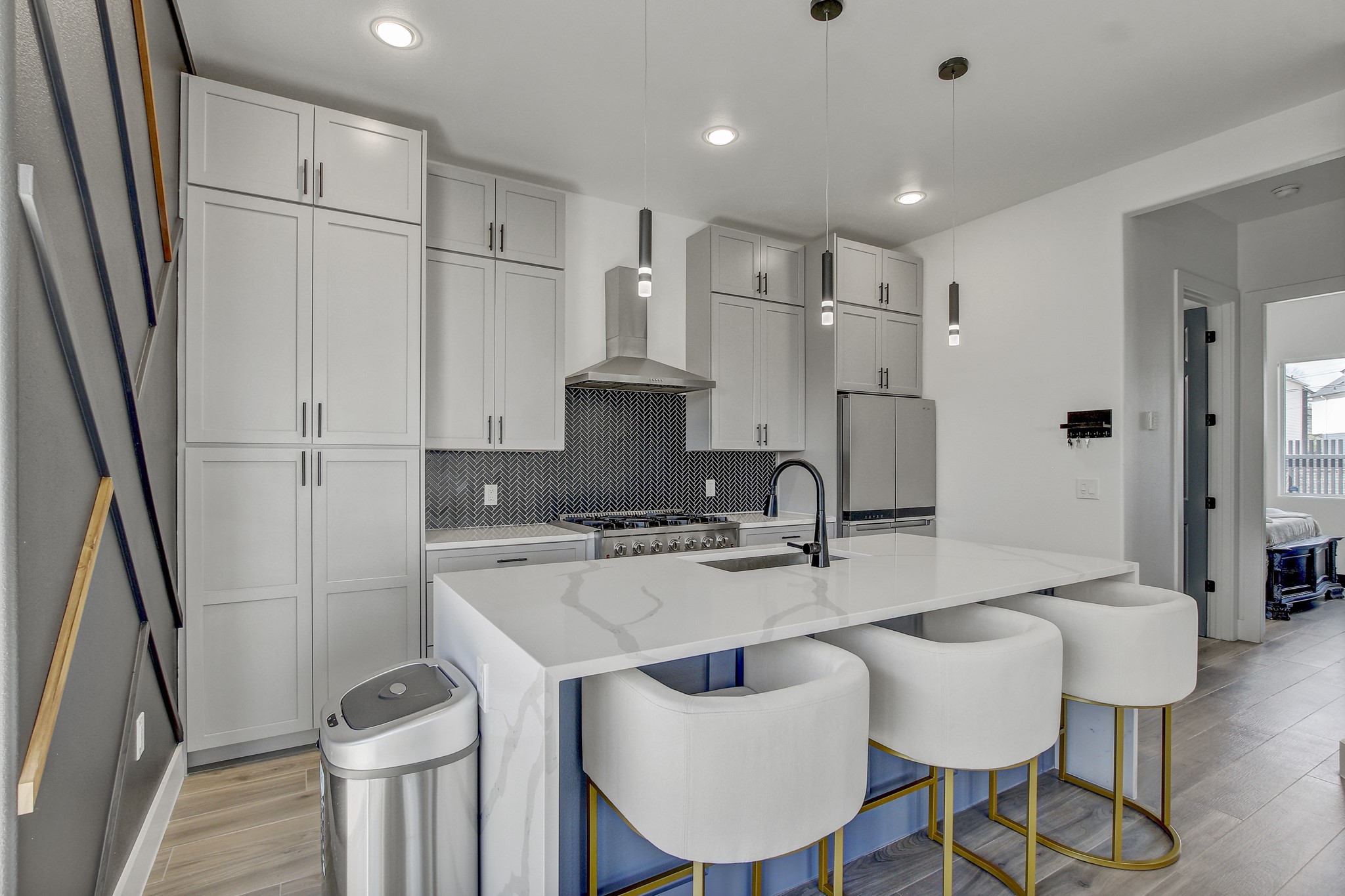 4703 Louis Avenue, Unit A Austin, TX 78721 - Photo 11 of 35 Kitchen with light stone countertops, a kitchen island with sink, a kitchen bar, decorative light fixtures, and backsplash