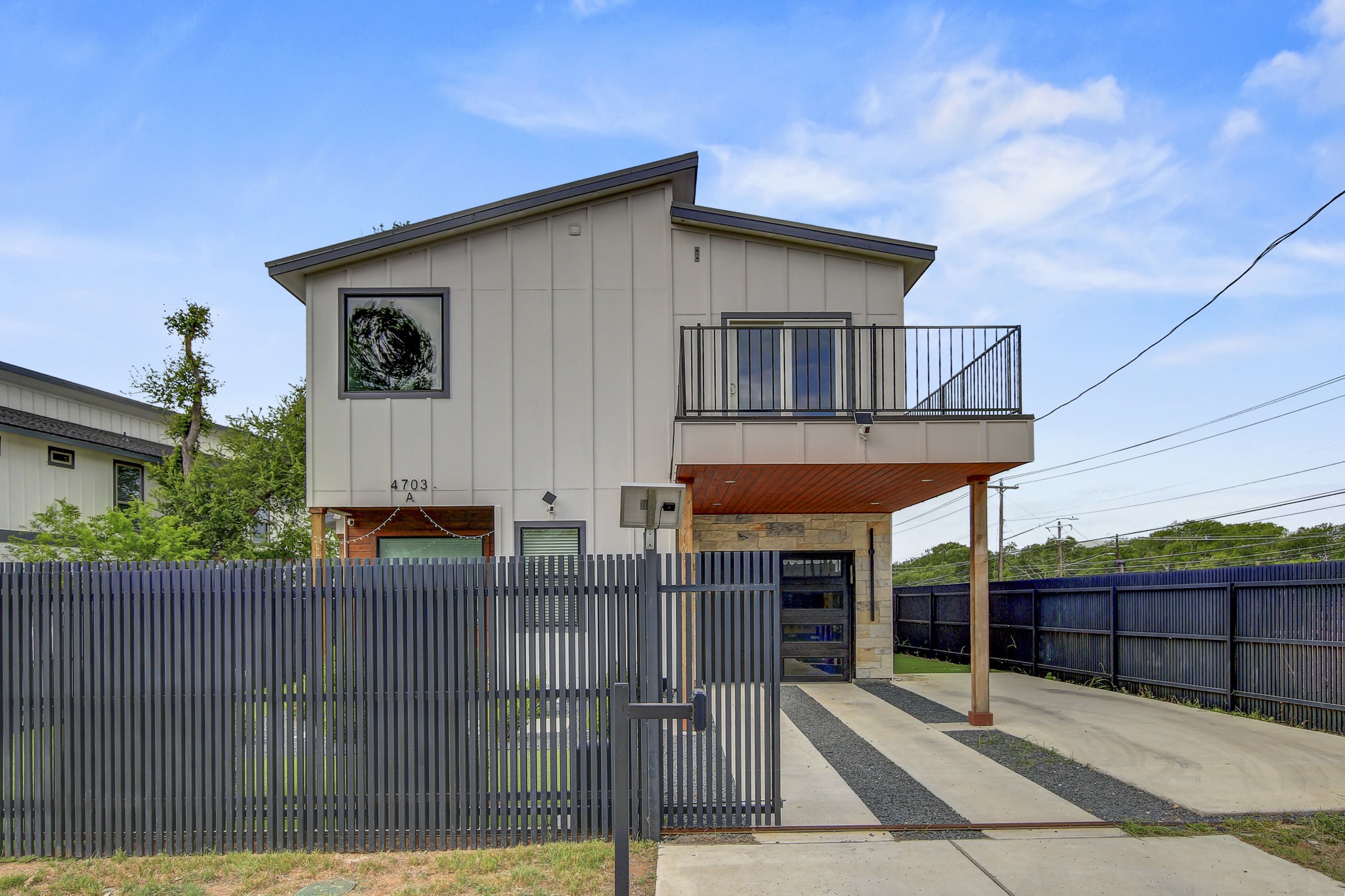 4703 Louis Avenue, Unit A Austin, TX 78721 - Photo 31 of 35 View of front of home featuring board and batten siding, a fenced front yard, a balcony, and driveway