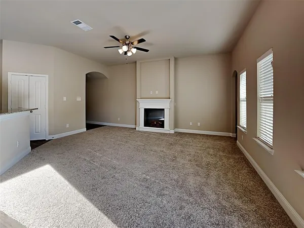 an empty room with windows and fireplace