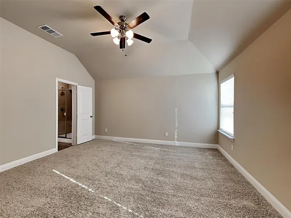 an empty room with chandelier fan and windows