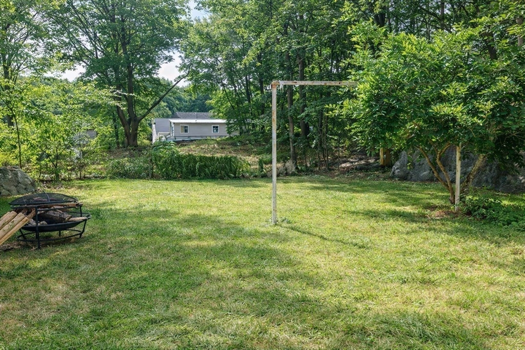 58 Bennett Street, Unit 1 Wakefield, MA 01880 - Photo 12 of 17 a view of a chair and table in the yard and large trees