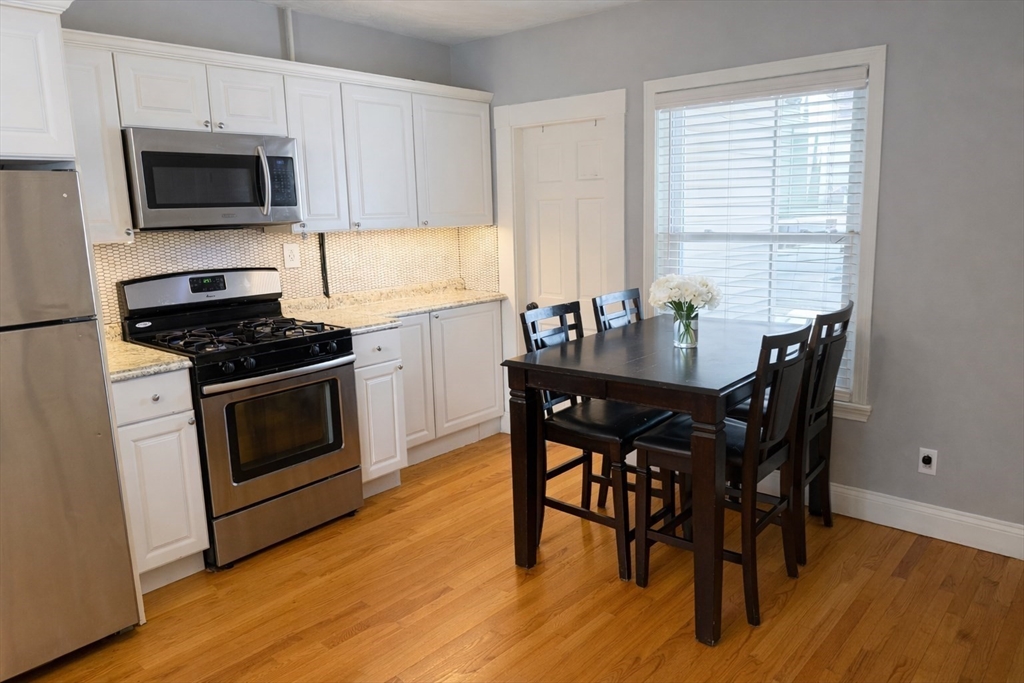 58 Bennett Street, Unit 1 Wakefield, MA 01880 - Photo 3 of 17 a kitchen with a stove a microwave and wooden floor
