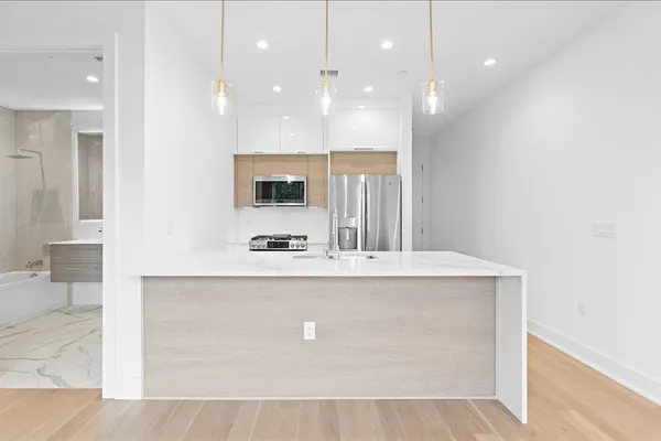 a view of a kitchen with kitchen island a sink stainless steel appliances and cabinets