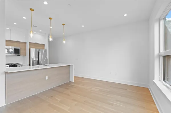 a living room with stainless steel appliances furniture a flat screen tv and kitchen view