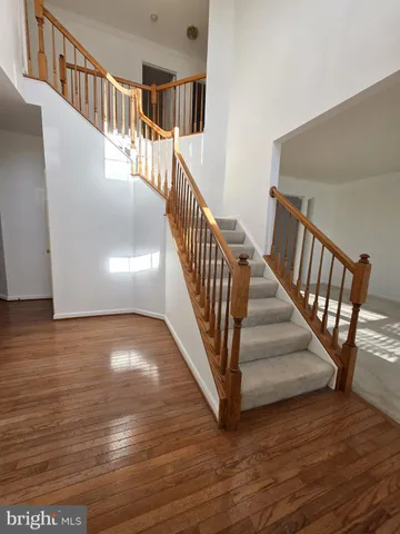 a view of staircase with wooden floor and pendant lights