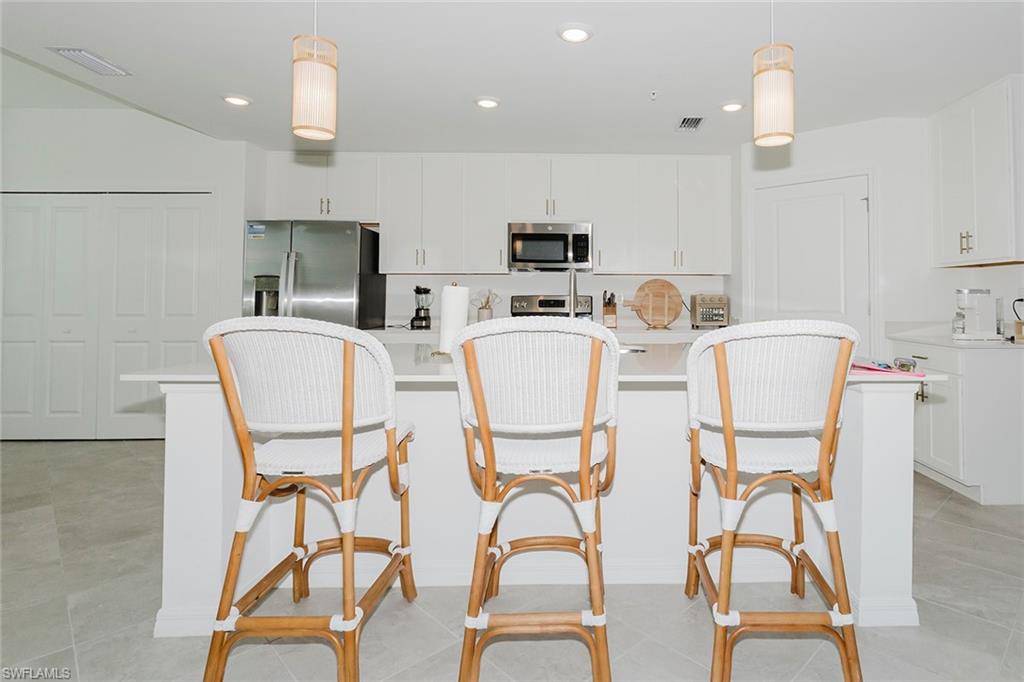 5445 Double Eagle Circle, Unit 3013 Ave Maria, FL 34142 - Photo 4 of 41 a dining room with stainless steel appliances kitchen island granite countertop a dining table chairs and a refrigerator