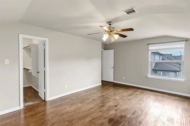 a view of an empty room with a window and wooden floor