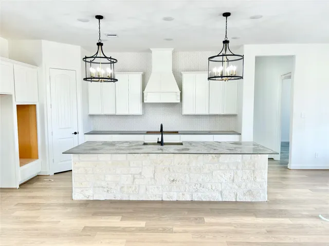 a kitchen with stainless steel appliances granite countertop a sink a stove a refrigerator and island with wooden floor