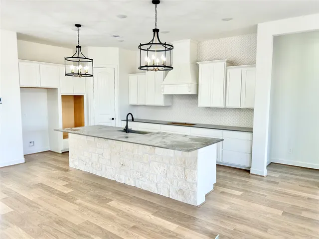 a kitchen with kitchen island granite countertop a stove a sink and dishwasher with wooden floor
