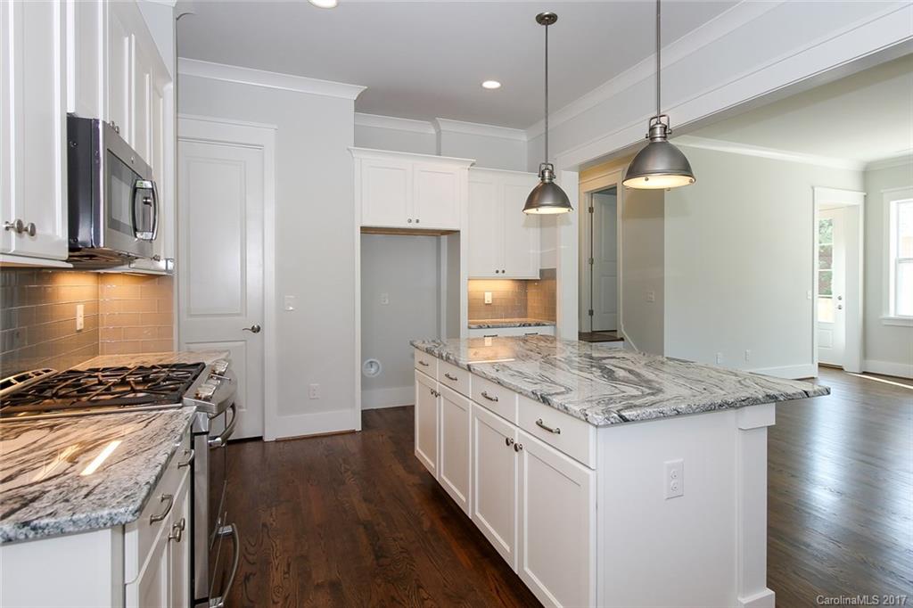 904 Millbrook Road, Unit 7A Charlotte, NC 28211 - Photo 5 of 22 a kitchen with stainless steel appliances granite countertop a stove a refrigerator and a sink with wooden floor