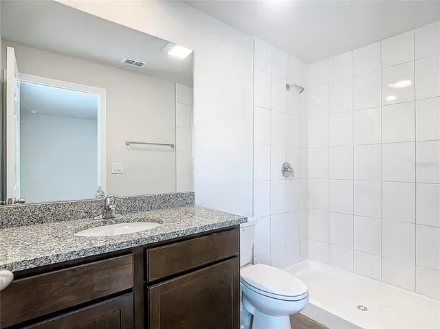 a bathroom with a granite countertop sink a toilet and shower