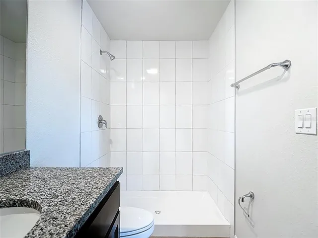 a bathroom with a granite countertop sink a toilet and shower