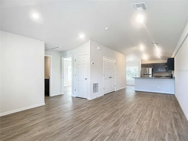 a view of a big room with wooden floor and a kitchen