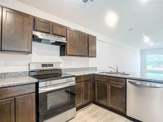 a kitchen with stainless steel appliances granite countertop a sink stove and cabinets