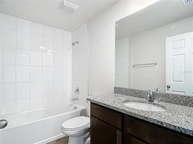 a bathroom with a granite countertop sink a toilet and shower