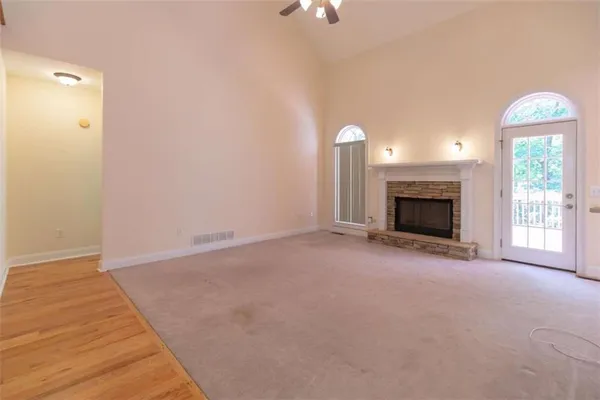 an empty room with chandelier fan and windows