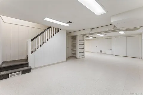 a view of an empty room with stairs and a window