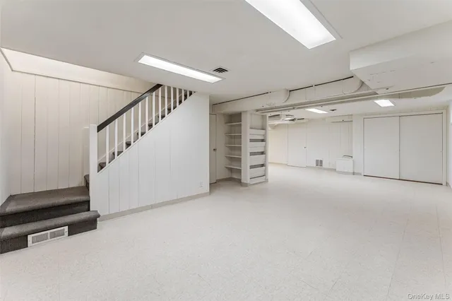 a view of an empty room with stairs and a window