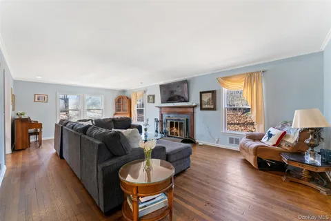 a living room with furniture a fireplace a flat screen tv and a large window