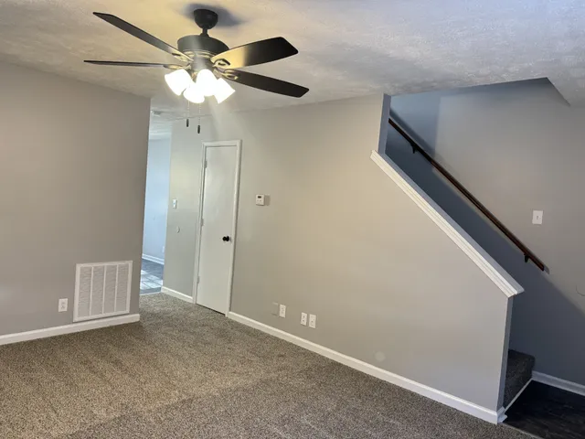 a view of an empty room with a chandelier fan