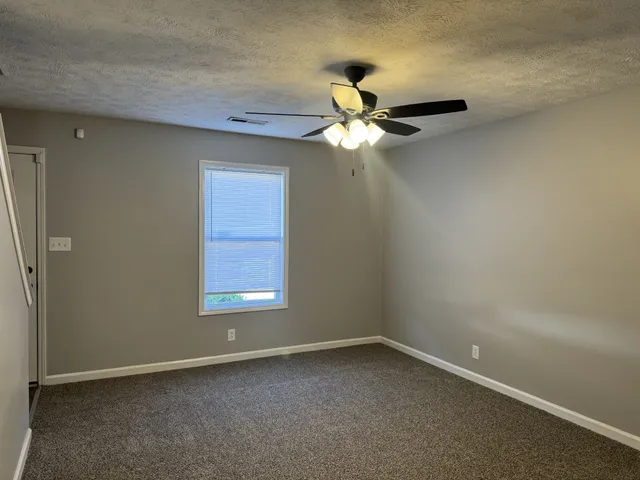 an empty room with a window and a fan