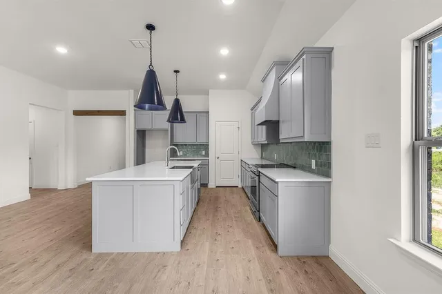 a kitchen with stainless steel appliances granite countertop a sink a stove a refrigerator and island with wooden floor