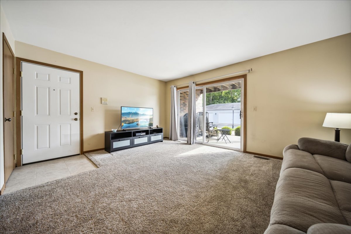 935 Golf Course Road, Unit 1 Crystal Lake, IL 60014 - Photo 3 of 10 a living room with furniture a window and a flat screen tv