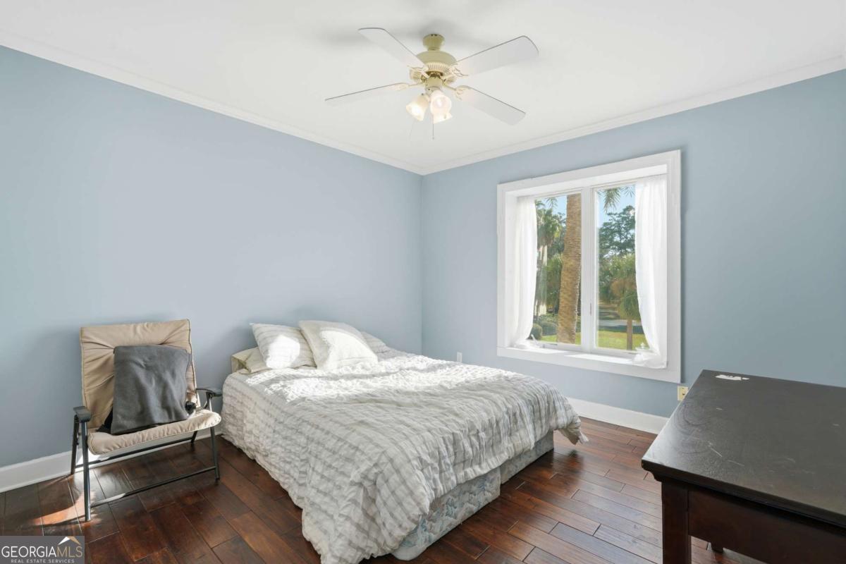 700 Wilmington Island Road, Unit 201 Savannah, GA 31410 - Photo 26 of 51 a bedroom with a bed and a desk with wooden floor