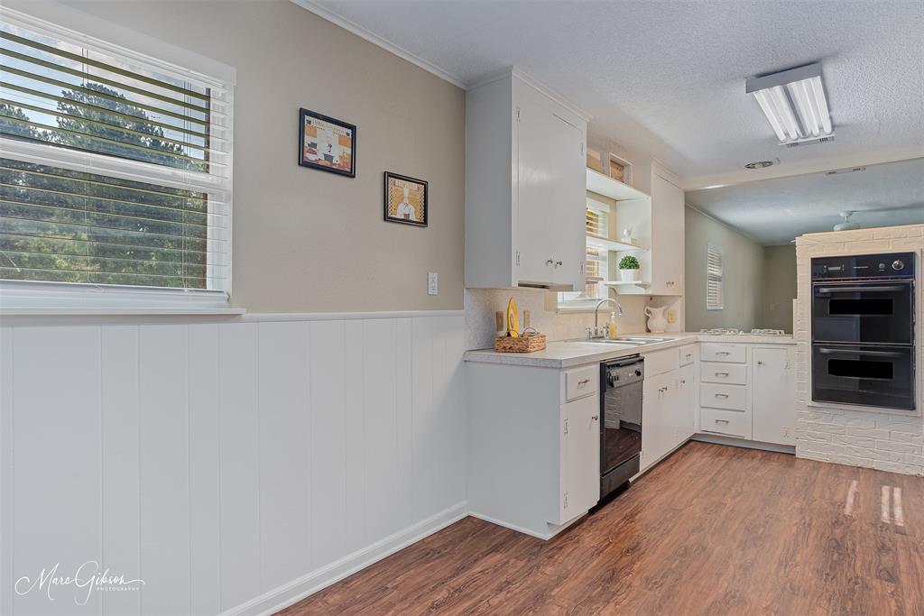 9342 Dean Road Shreveport, LA 71118 - Photo 7 of 18 Kitchen featuring wood-finish flooring, white cabinetry, a built-in double oven, dishwasher, and a window with horizontal blinds