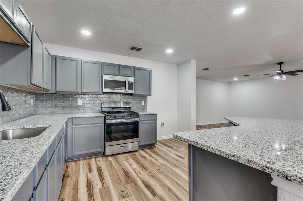 6524 Willow Oak Court Fort Worth, TX 76112 - Photo 11 of 15 a kitchen with kitchen island granite countertop a sink stove and refrigerator