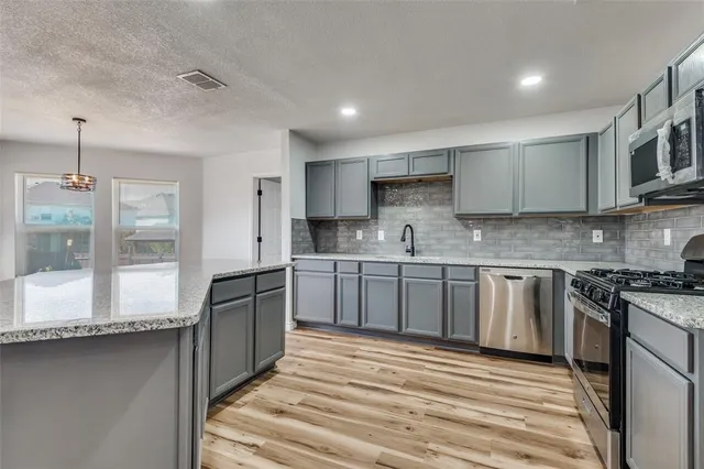 a kitchen with stainless steel appliances granite countertop a stove a sink and a refrigerator