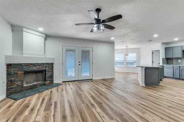 a view of an empty room with wooden floor a fireplace and a window