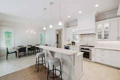 a kitchen with stainless steel appliances granite countertop a stove top oven a sink dishwasher a dining table and chairs with wooden floor