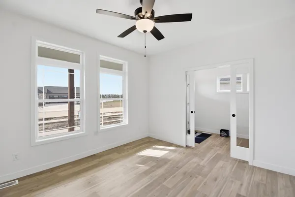 a view of empty room with wooden floor and fan