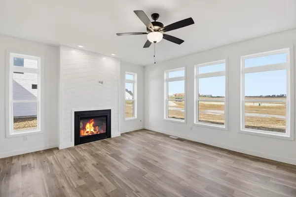 a view of an empty room with wooden floor fireplace and a window