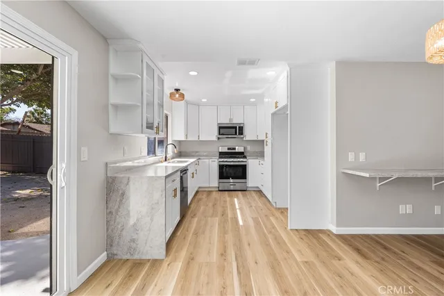 a kitchen with kitchen island wooden floors appliances and cabinets