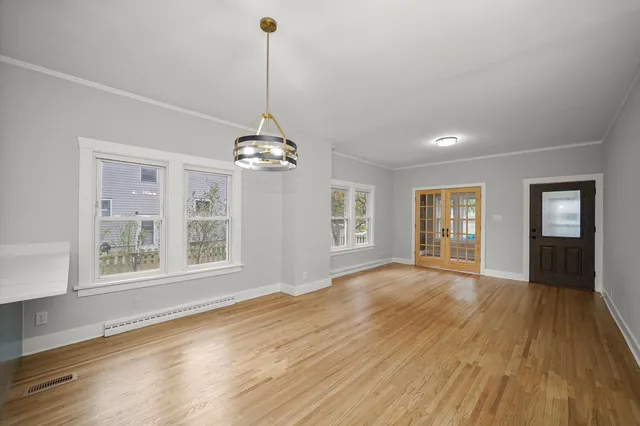 a view of an empty room with wooden floor and a window