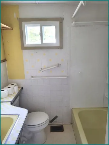 a white toilet sitting next to a bathroom sink and tub