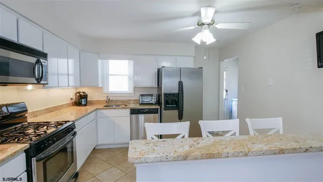 a kitchen with granite countertop a sink stainless steel appliances and white cabinets