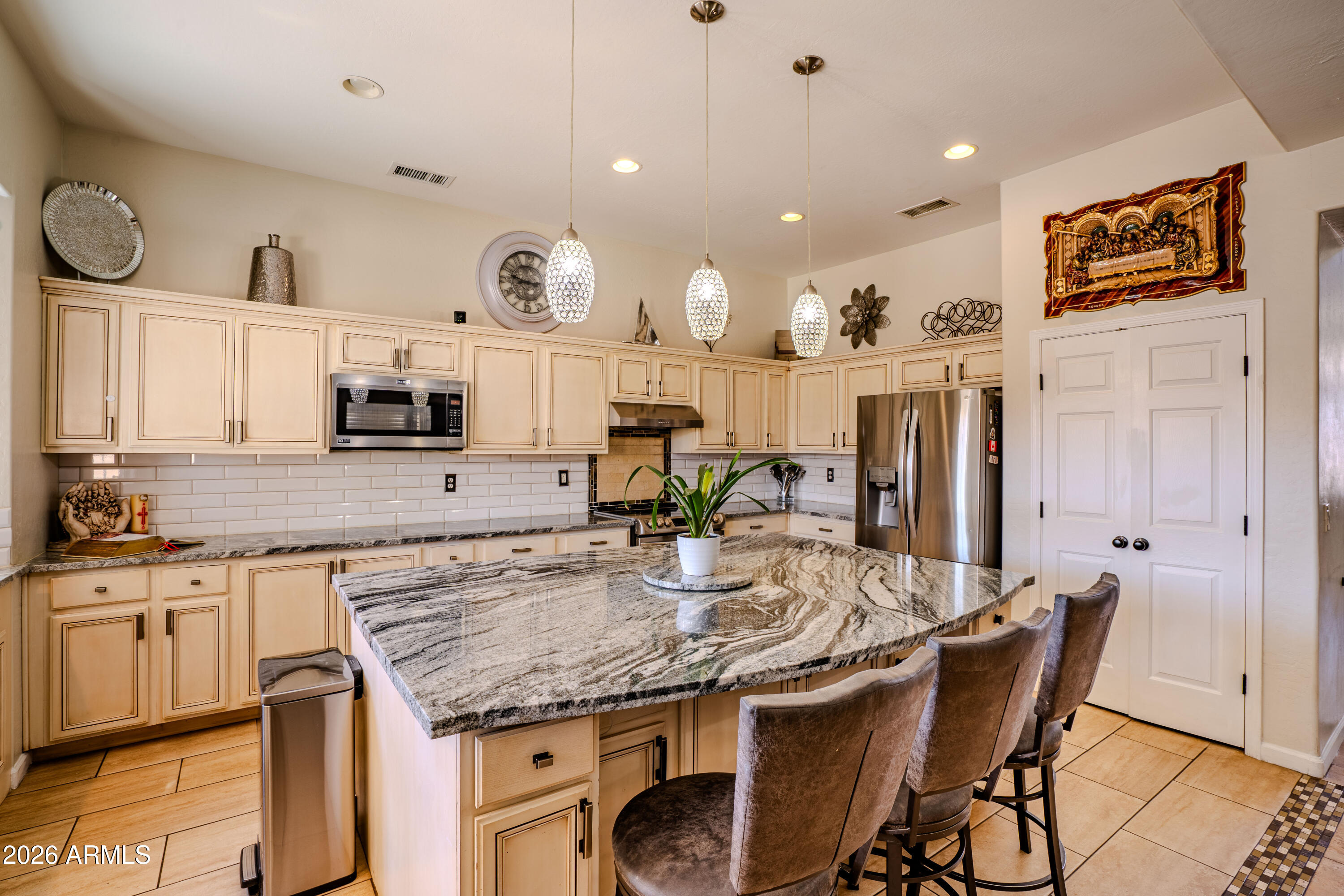 5137 West Grenadine Road Laveen, AZ 85339 - Photo 12 of 53 a kitchen with stainless steel appliances granite countertop a kitchen island and chairs in it