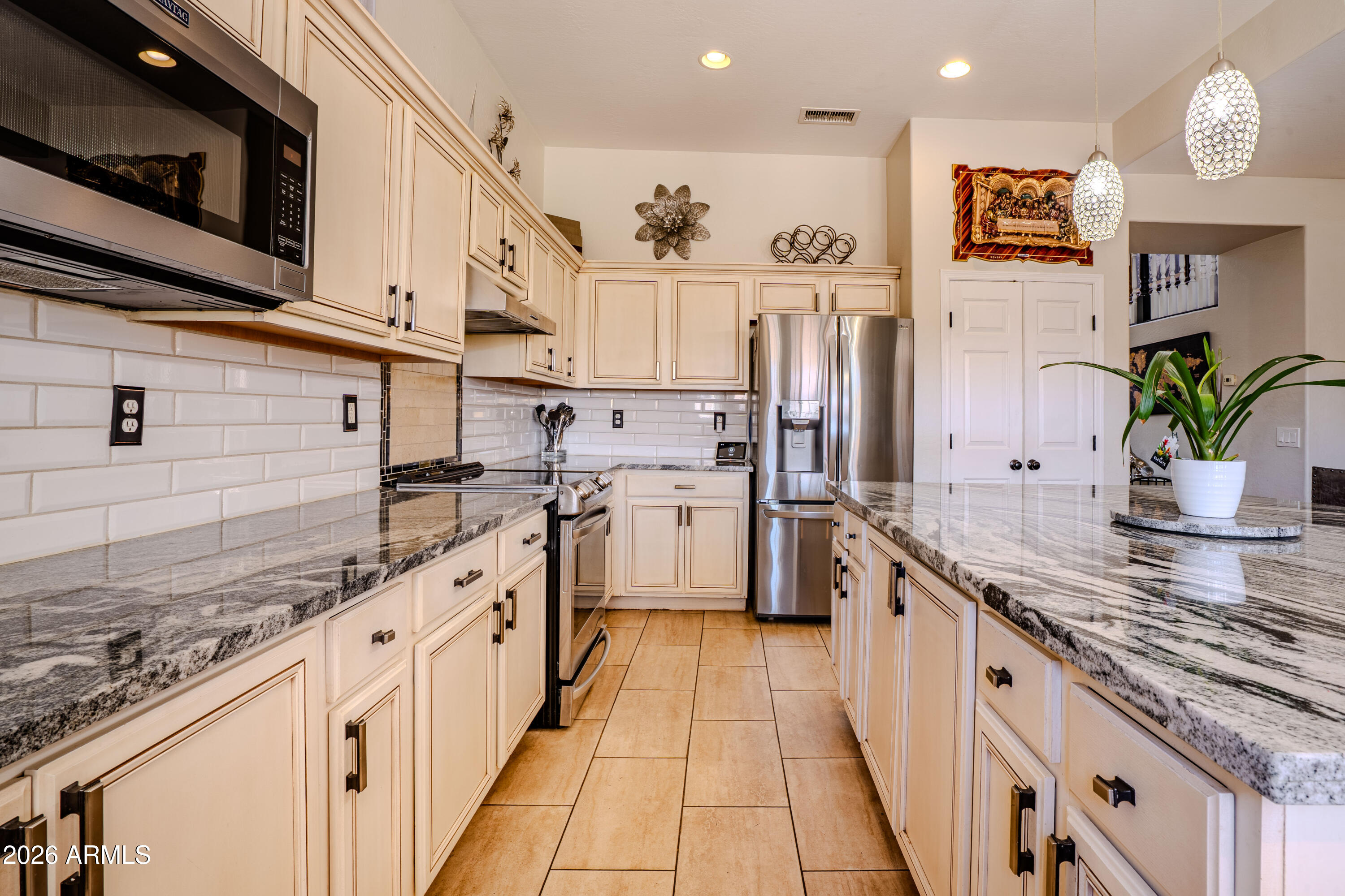 5137 West Grenadine Road Laveen, AZ 85339 - Photo 16 of 53 a large white kitchen with stainless steel appliances granite countertop lots of white cabinets a stove and a sink