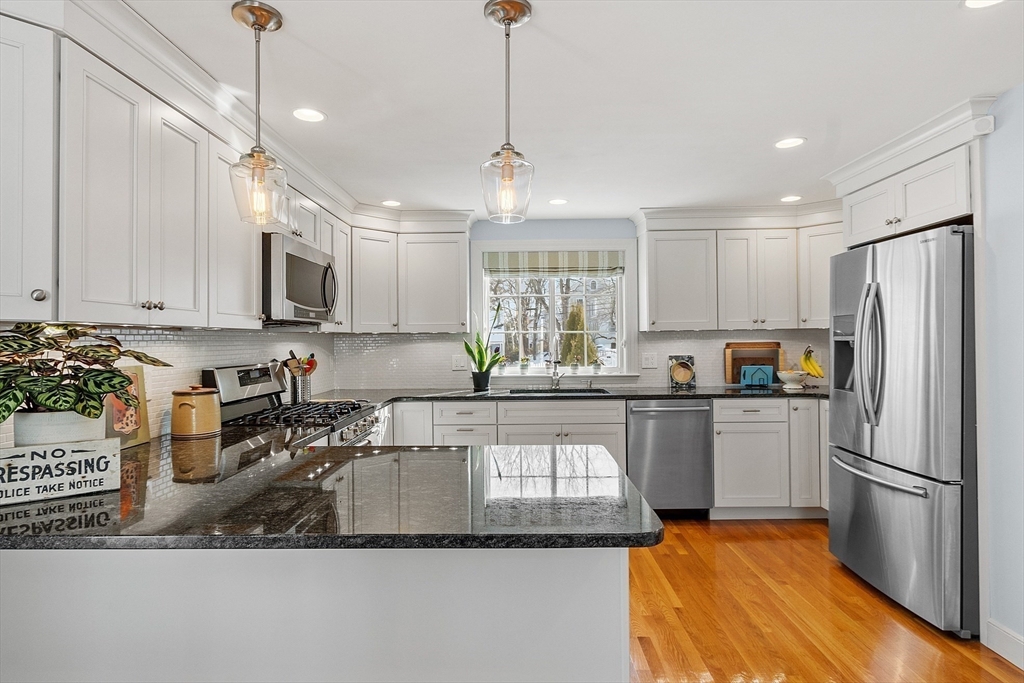 88 Menotomy Road Arlington, MA 02476 - Photo 6 of 40 a kitchen with stainless steel appliances granite countertop a refrigerator a sink dishwasher a s stove top oven a large island with white cabinets and wooden floor