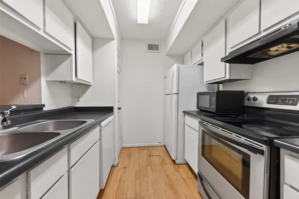 a kitchen with granite countertop a sink stove and refrigerator