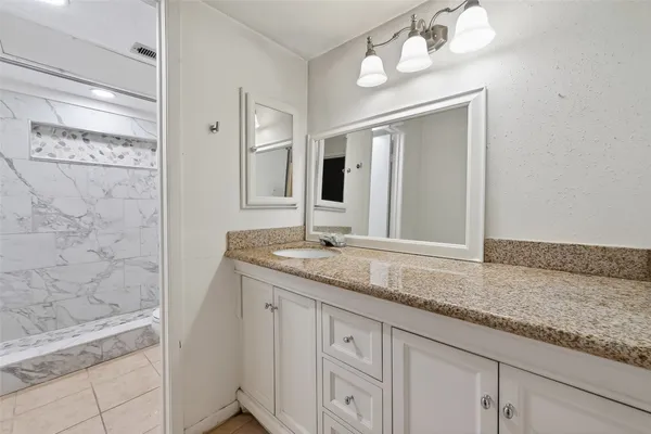 a bathroom with a granite countertop sink a mirror and a shower