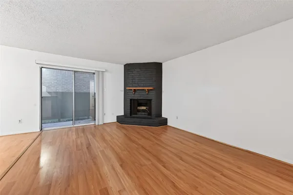an empty room with wooden floor fireplace and windows