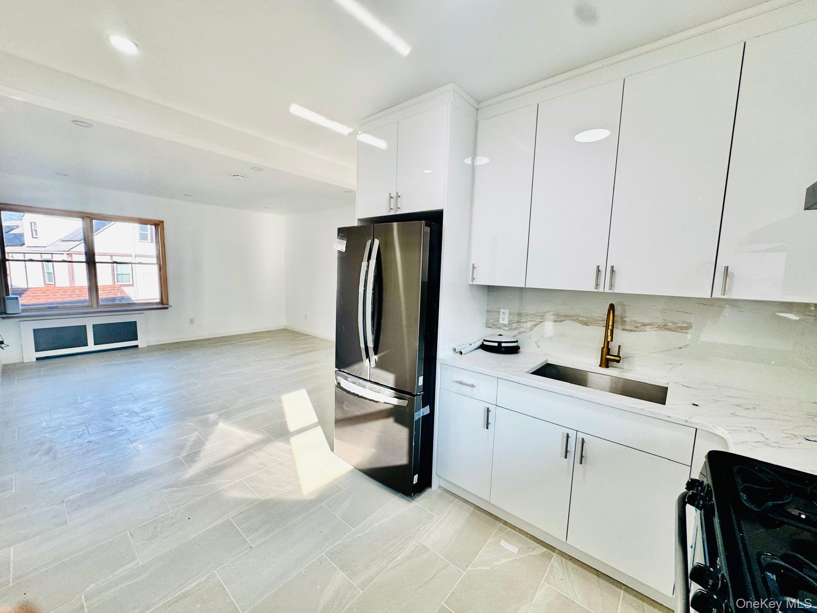 63-87 Fitchett Street, Unit 2 Queens, NY 11374 - Photo 3 of 12 a kitchen with a sink a refrigerator and cabinets