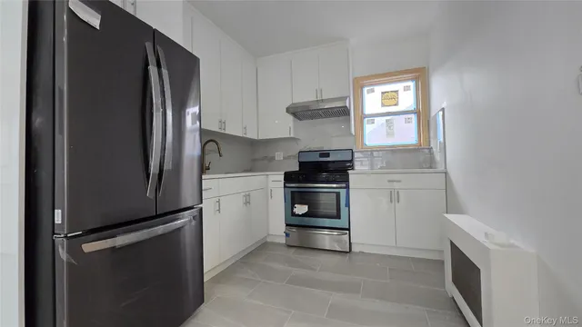 a kitchen with white cabinets and stainless steel appliances