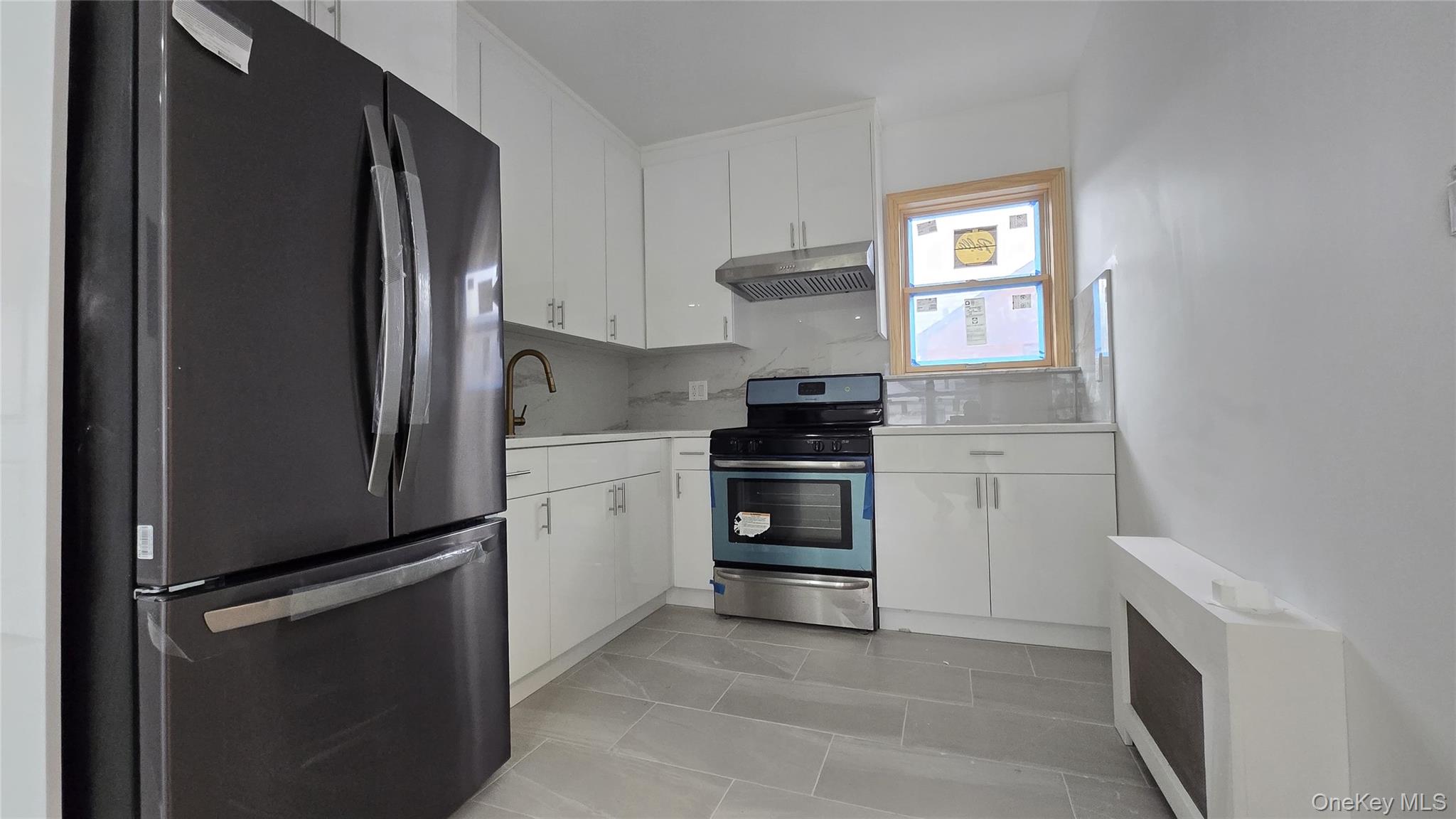 63-87 Fitchett Street, Unit 2 Queens, NY 11374 - Photo 5 of 12 a kitchen with white cabinets and stainless steel appliances