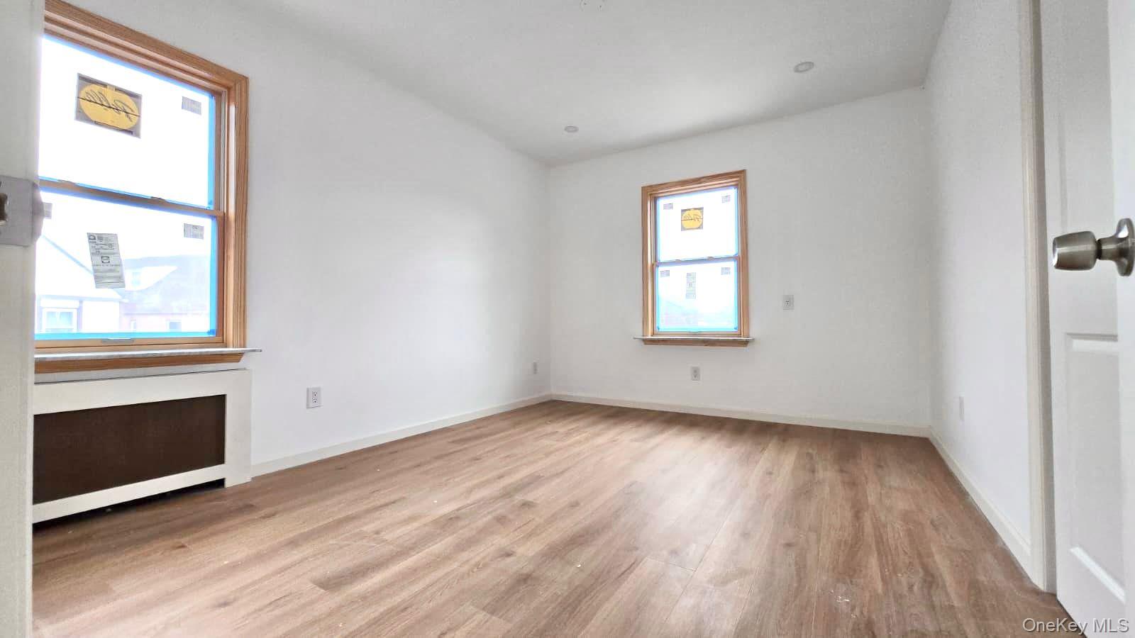 63-87 Fitchett Street, Unit 2 Queens, NY 11374 - Photo 6 of 12 an empty room with wooden floor fireplace and windows